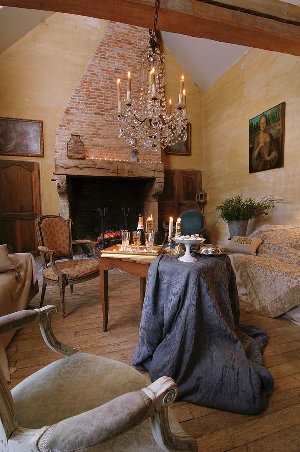 Chandelier With Lit Candles In Rustic Living Room With Traditional Seating And Brocade Tablecloth Draped On Simple Wooden Table Photograph by Christophe Madamour