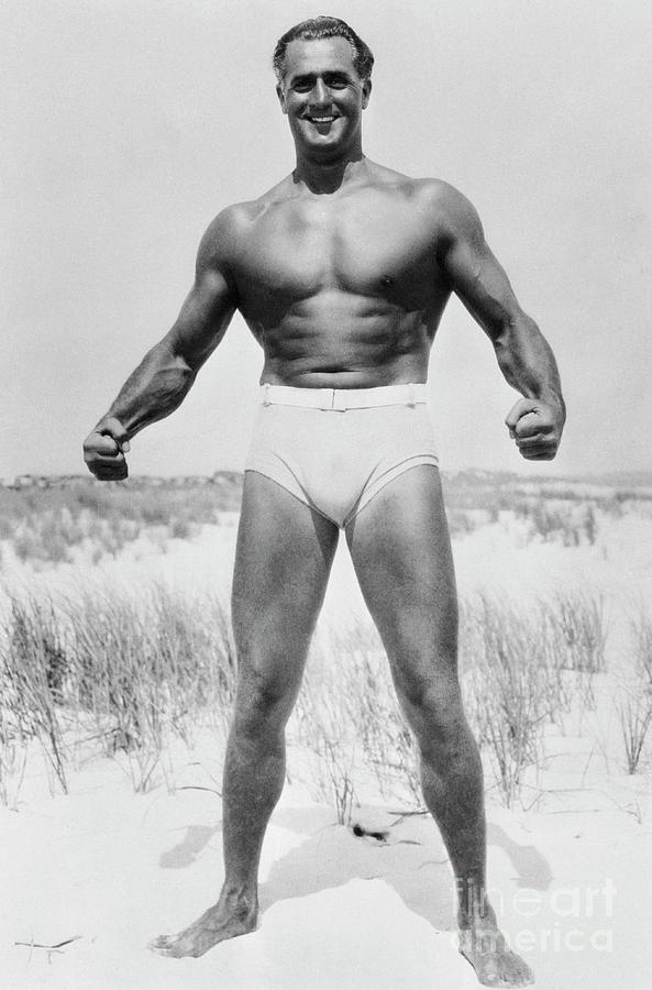 Charles Atlas Flexing Muscles On Beach Photograph by Bettmann