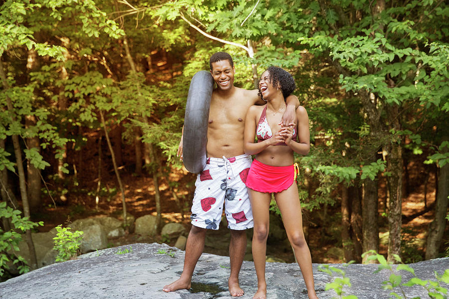 Tree Photograph - Cheerful Couple In Bathing Suits Standing On Rock Against Trees In Forest by Cavan Images