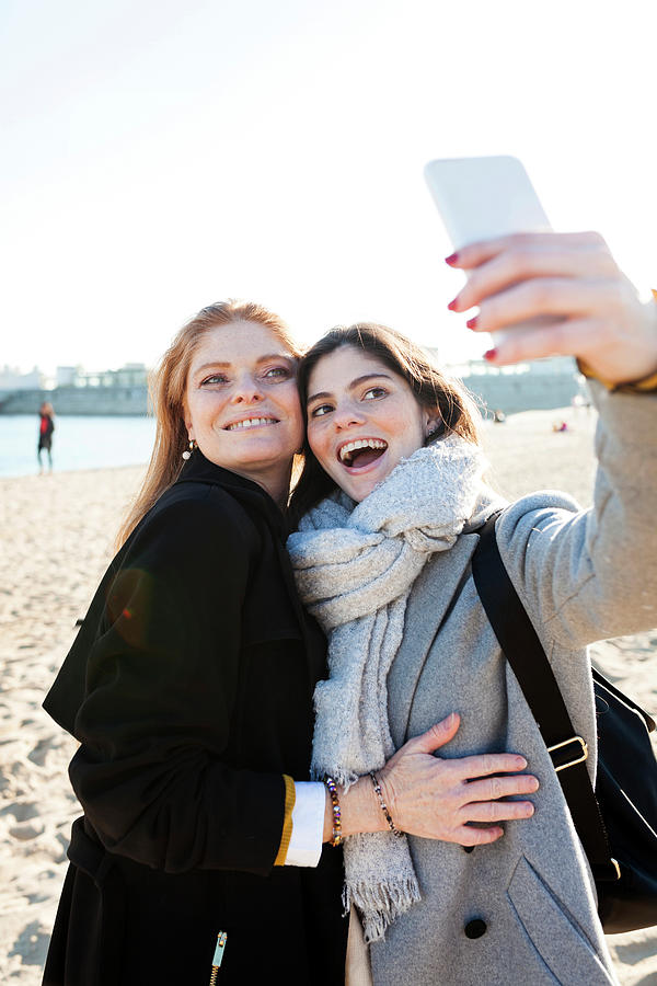 Cheerful Mother And Daughter Taking Selfie With Smart Phone At Beach