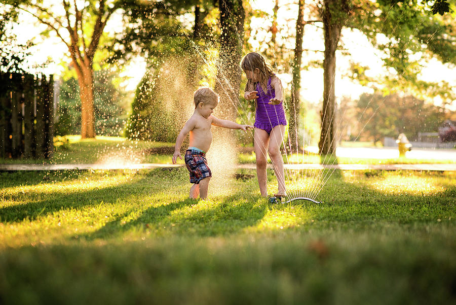 Cheerful Siblings Playing In Sprinkler Photograph by Cavan Images ...