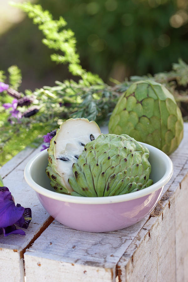 Cherimoya, Whole And Halved On A Wooden Box Outdoors Photograph by Angelica Linnhoff