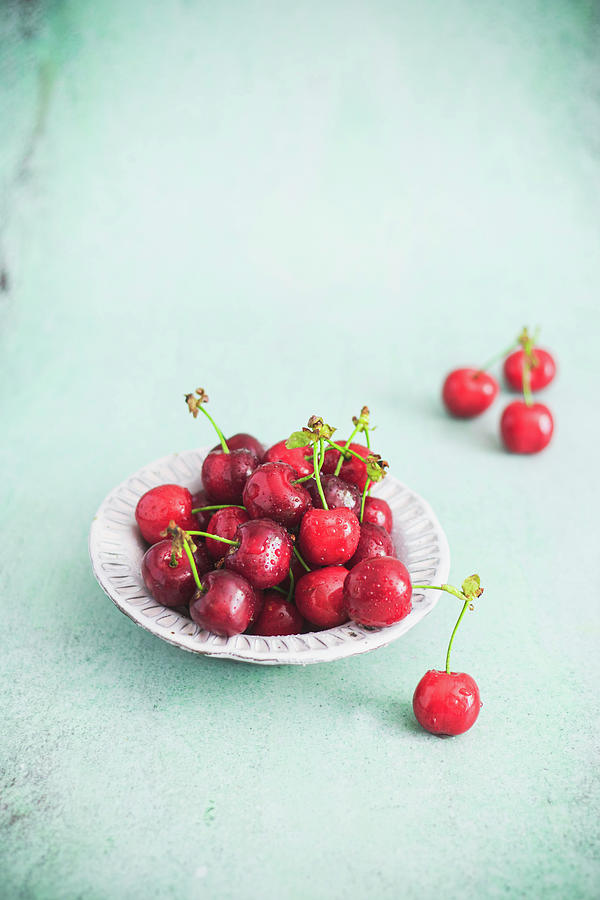 Cherries In A Bowl On A Light Background Photograph by Karolina Nicpon