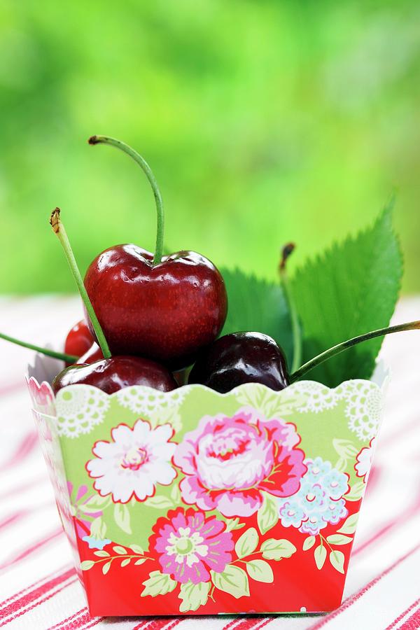 Cherries In Cardboard Punnet With Floral Pattern Photograph by Angelica Linnhoff