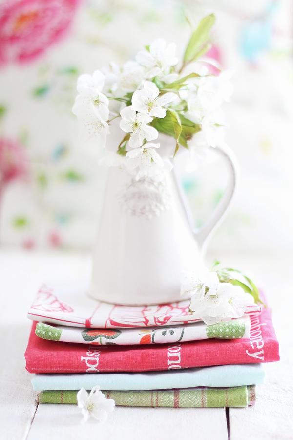 Cherry Blossom In Ceramic Vase On Stacked Tea Towels Photograph by Sylvia E.k Photography