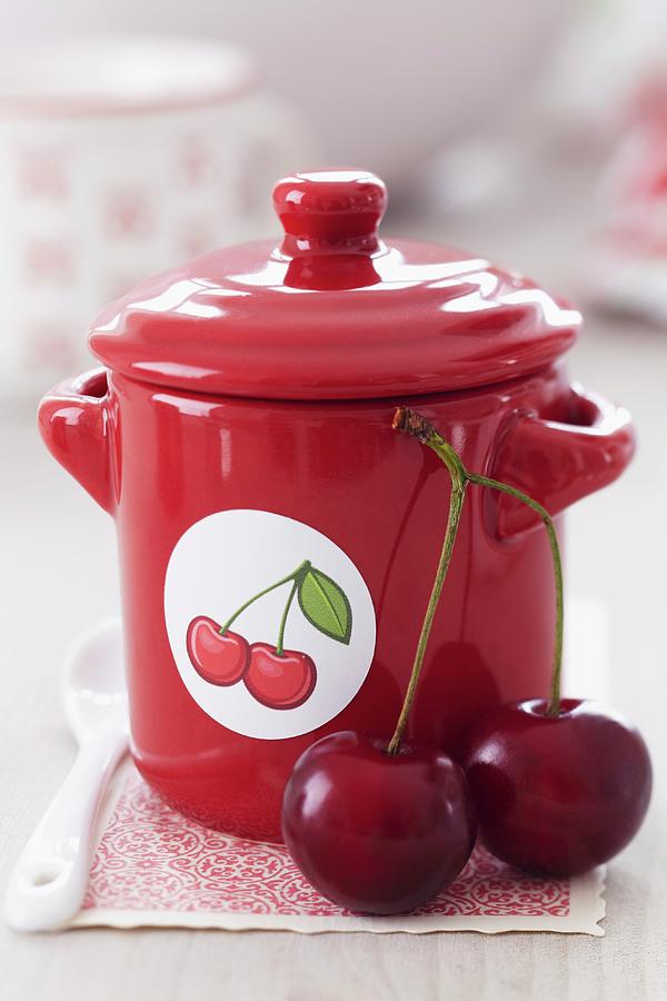 Cherry Jam In A Red Pot With A Cherry Sticker Photograph by Taube, Franziska