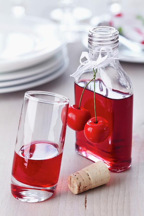 Cherry Liqueur In A Small Bottle Decorated With A Fake Cherry, Some Poured Into A Glass Photograph by Taube, Franziska