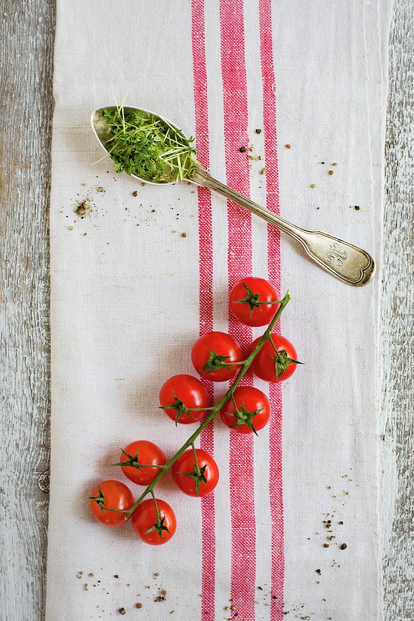 Cherry Tomatoes On The Vine And A Spoonful Of Cress On A Tea Towel Photograph by Tina Engel