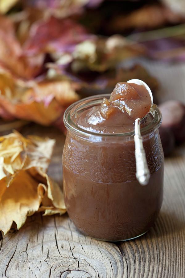 Chestnut Cream In A Jar On A Wooden Surface With Autumnal Leaves Photograph by Hilde Mche