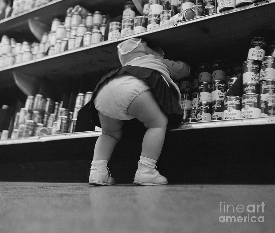 Child Grabbing Cans From Shelf Photograph by Bettmann