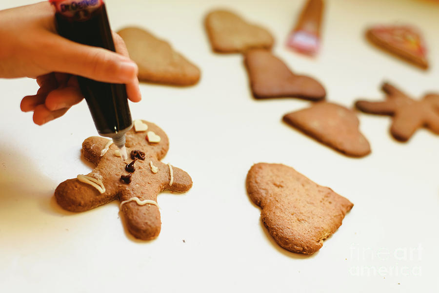 Child hands preparing homemade gingerbread cookies with colorful decorations. Photograph by Joaquin Corbalan