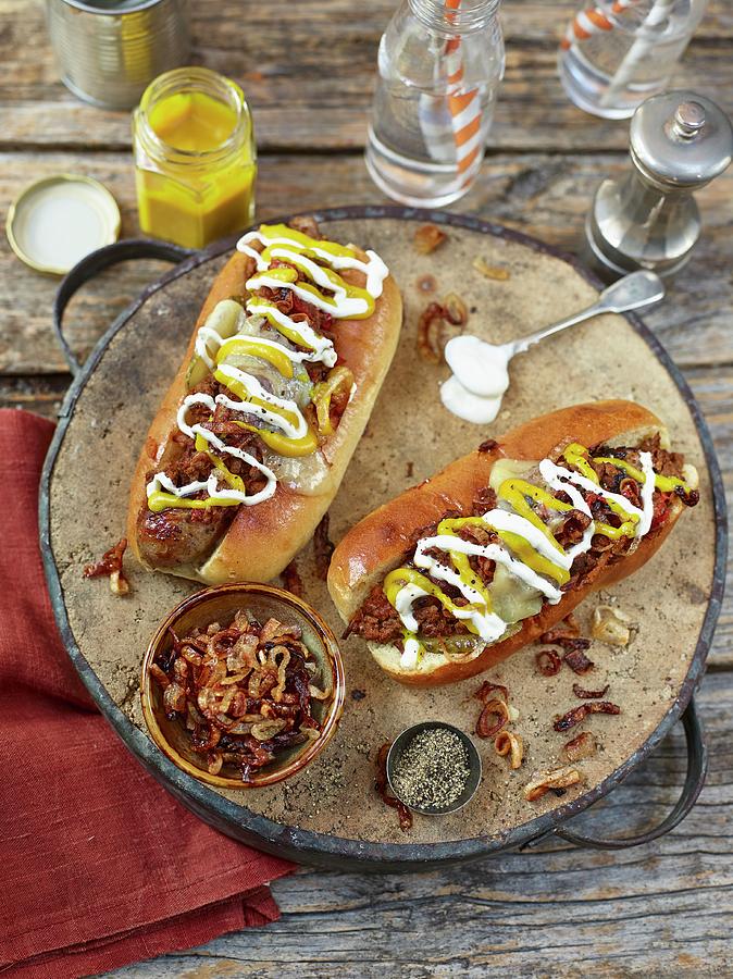 Chilli Hot Dogs Topped With Fried Onion, Mustard And Mayonaise Photograph by Dan Jones