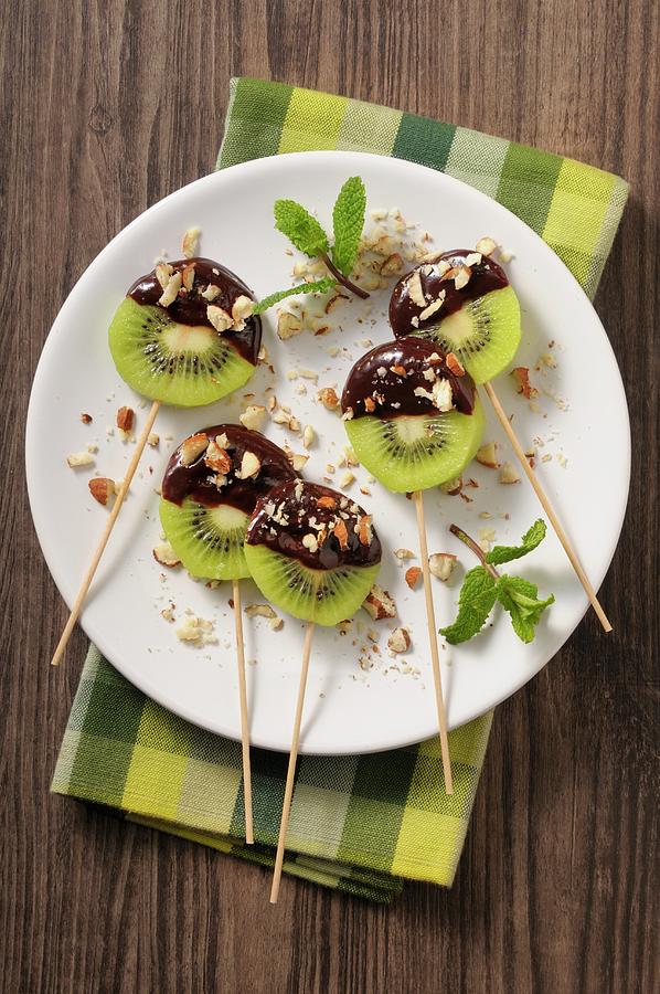 Chocolate And Kiwi Lollies With Chopped Nuts Photograph by Jean-christophe Riou