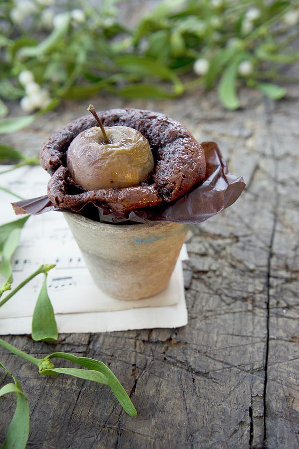 Chocolate Cake With Apple In An Earthenware Pot With A Sprig Of Mistletoe On A Piece Of Sheet Music Photograph by Martina Schindler