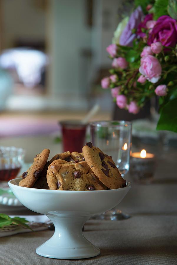 Chocolate-chip Cookies In White China Dish On Set Table Photograph by Christophe Madamour
