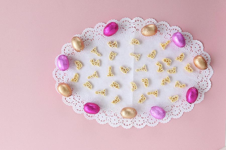 Chocolate Easter Eggs And Rabbit-shaped Pasta On A White Doily Photograph by Regina Hippel