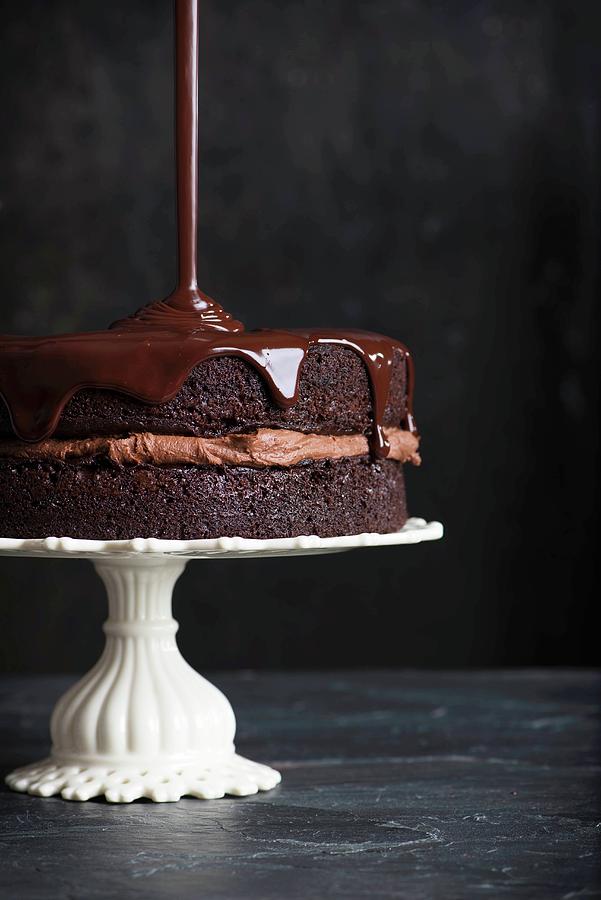 Chocolate Glaze Being Poured Over A Chocolate Cake Photograph by Farrell Scott