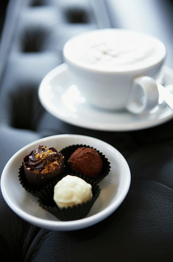 Chocolate Pralines And A Cappuccino Photograph by Myles New
