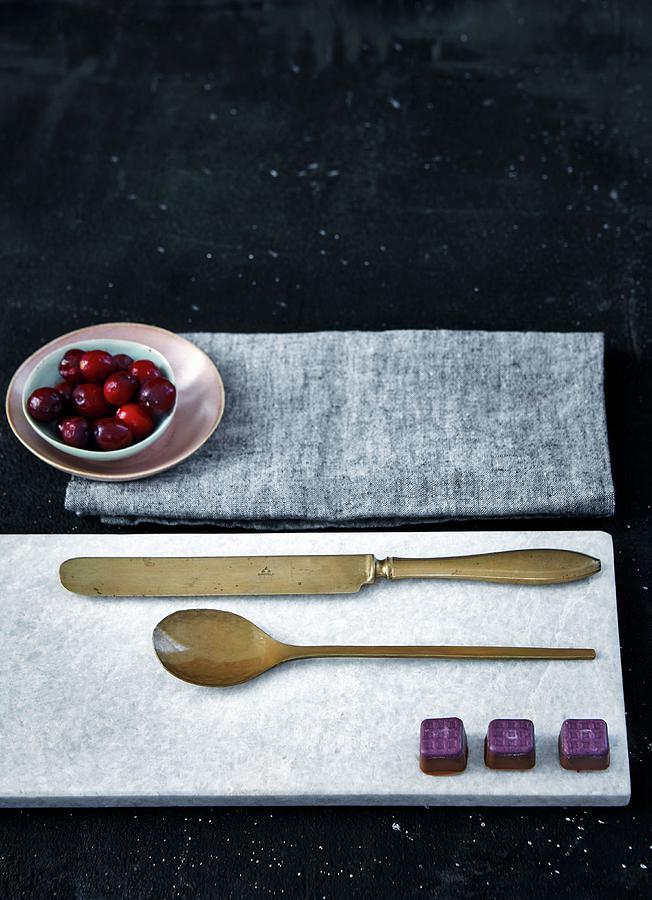 Chocolates And Cutlery On Marble Board And Small Bowl Of Cranberries On Cloth Photograph by Nina Struve