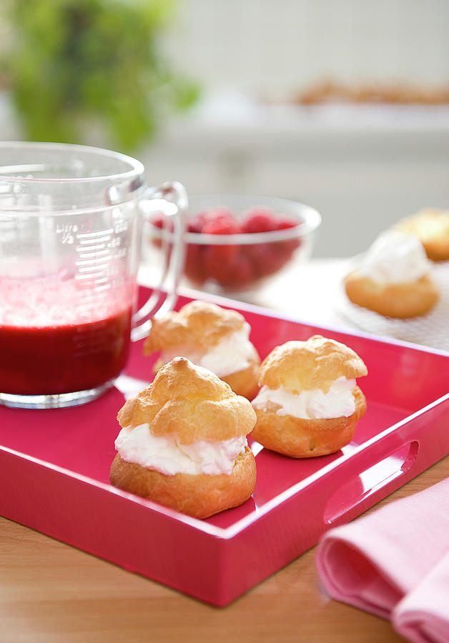 Choux Puffs Garnished With Whipped Cream And A Jug Of Raspberry Coulis Photograph by Bertram