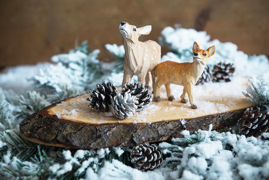 Christmas Arrangement Of Carved Deer Figurines On Slice Of Log And Snowy Branches Photograph by Veronika Studer