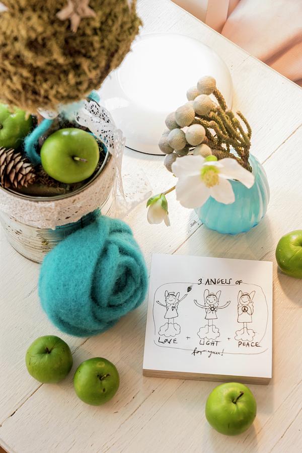 Christmas Arrangement Of Green Apples, Turquoise Felt Flower, Hellebore Flowers And Drawing On Piece Of Wood On Table Photograph by Bildhbsch