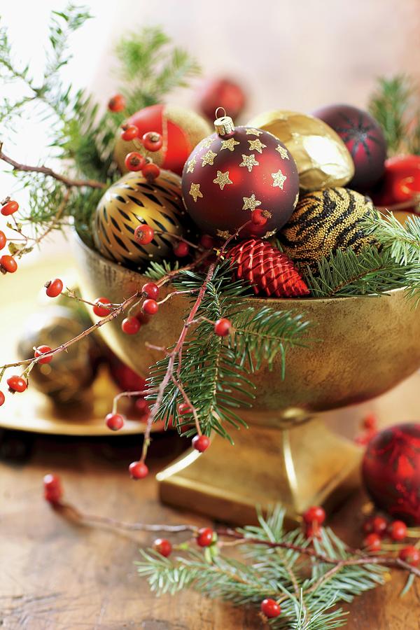 Christmas Baubles On Fir Branches And Sprigs Of Berries In Gilt Bowl Photograph by Biglife