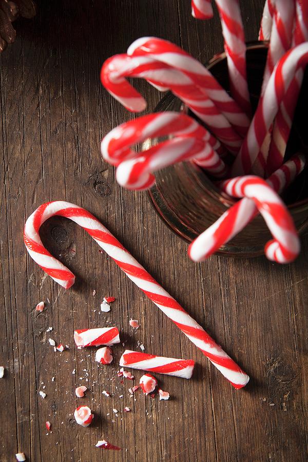 Christmas Candy Canes In A Gold Traditional Mug And One Cane On A Rustic Wooden Surface Photograph by Stacy Grant