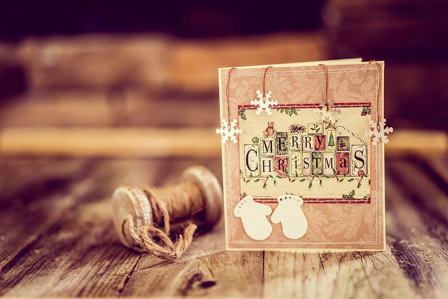 Christmas Card And Vintage Reel Of String On Rustic Wooden Surface Photograph by Alena Haurylik