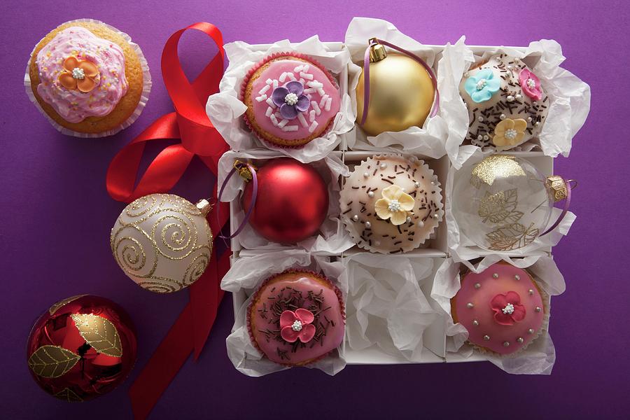 Christmas Cupcakes And Petit Fours Between Christmas Baubles Photograph by Blueberrystudio