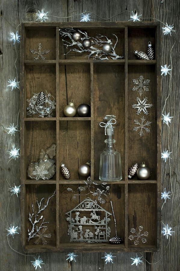Christmas Decorations In Old Wooden Display Case Surrounded By Star-shaped Fairy Lights Photograph by Achim Sass