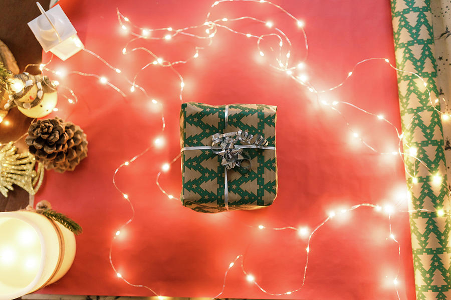 Christmas Photograph - Christmas Gift In A Wrapper In The Middle Of Decor And Gift Paper by Cavan Images