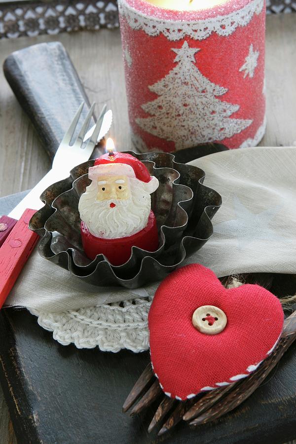 Christmas Table Decoration With Father Christmas Candle In Small Cake Tins, Cutlery And Fabric Heart Photograph by Regina Hippel