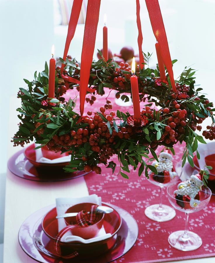 Christmas Table Set In Red And White Below Advent Crown Of Berries And Lit Candles Photograph by Matteo Manduzio