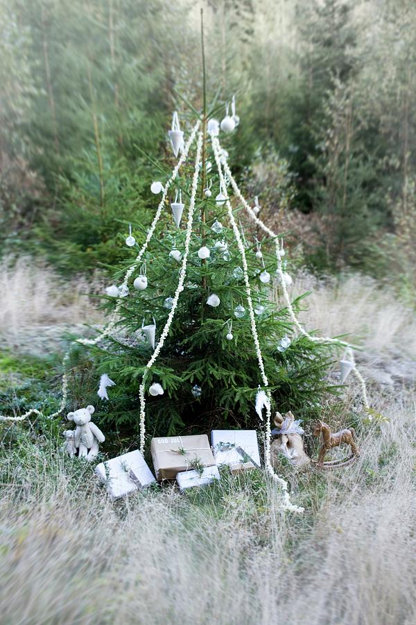 Christmas Tree Decorated With Baubles, Garlands And Wrapped Presents In Woodland Clearing Photograph by Annette Nordstrom