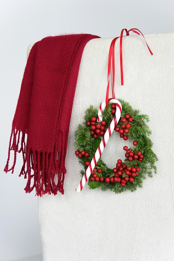 Christmas Wreath Of Holly Berries And Conifer Hanging On Chair Back With Candy Cane Photograph by Martina Schindler