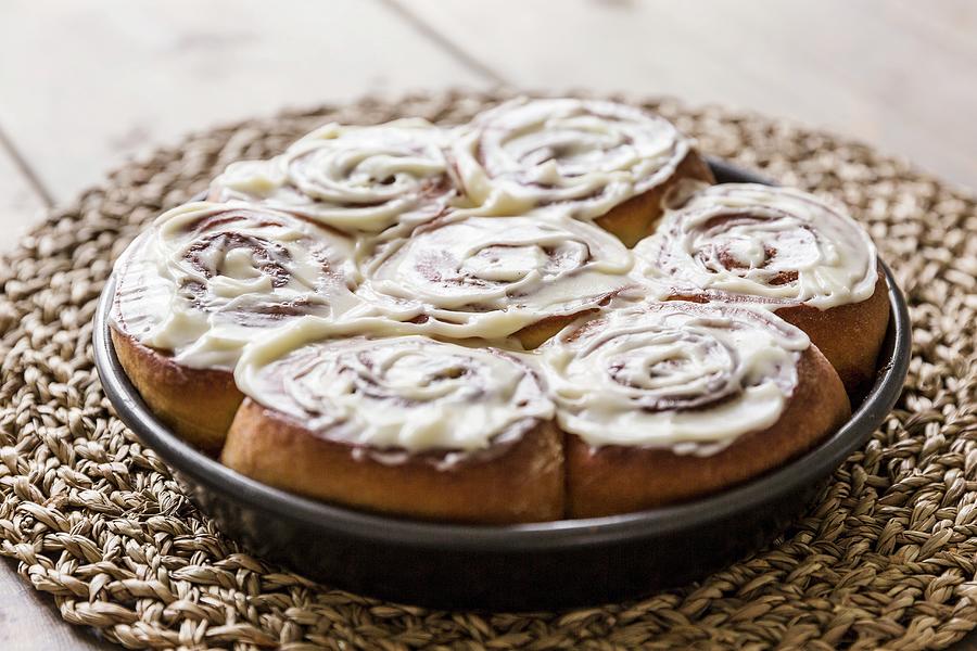 Cinnamon And Cardomom Buns In A Pan With Vanilla Cream Cheese Frosting Photograph by Sarah Coghill