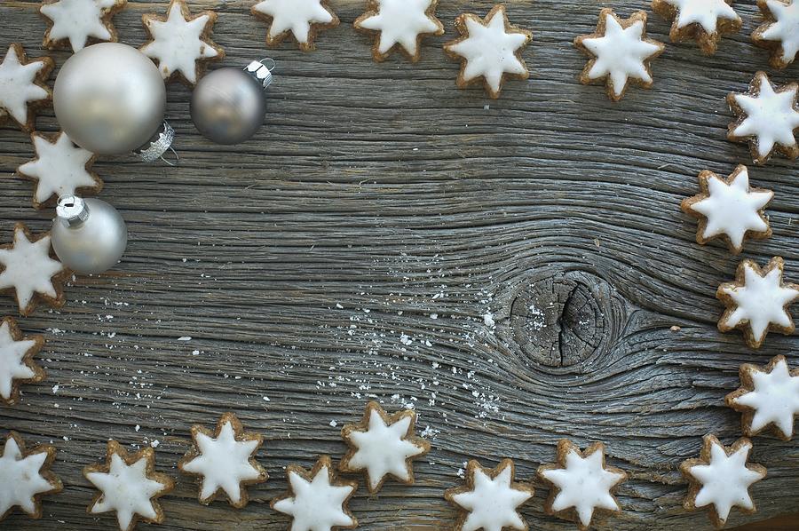 Cinnamon Stars And Christmas Tree Baubles On A Rustic Wooden Board Photograph by Achim Sass