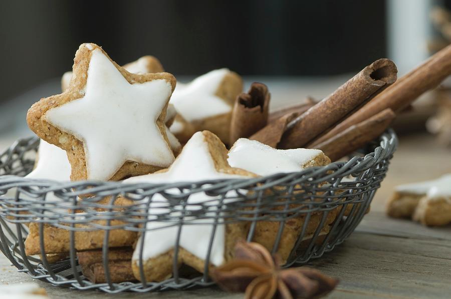 Cinnamon Stars And Cinnamon Sticks In A Basket On A Rustic Wooden Table Photograph by Achim Sass