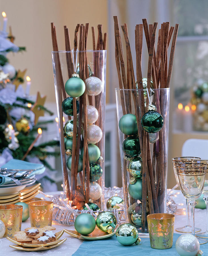 Cinnamon Sticks In Tall Glasses With Green And Cream Colored Balls Photograph by Friedrich Strauss