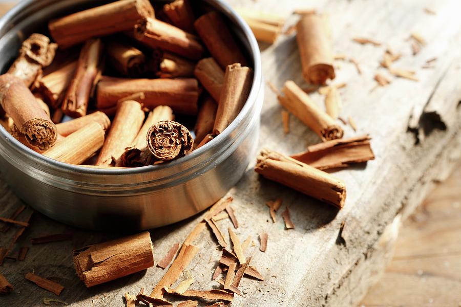 Cinnamon Sticks Inside And Next To A Tin On A Wooden Surface Photograph by Viola Cajo