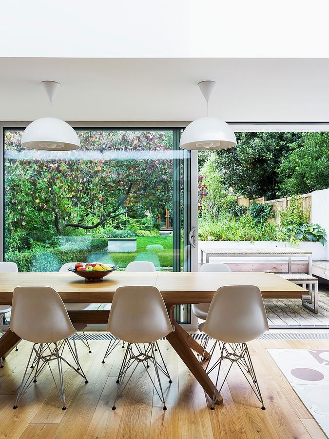 Classic Chairs And Modern Wooden Dining Table In Front Of Open Terrace Door With View Of Terrace And Garden Photograph by Simon Maxwell Photography