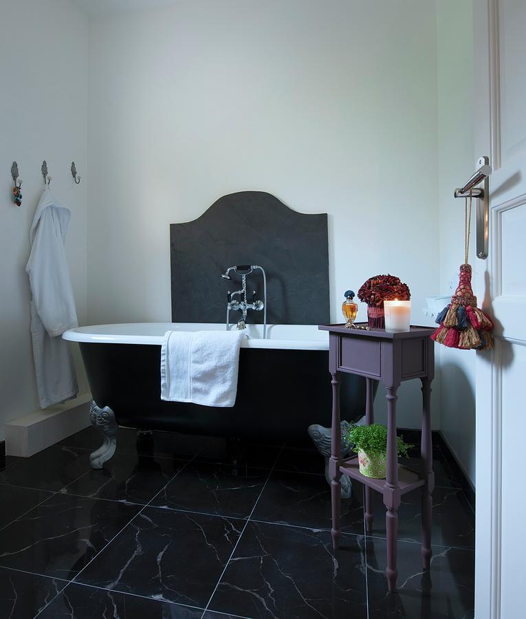 Clawfoot Bathtub And Small Table In Bathroom With Black Marble Floor ...