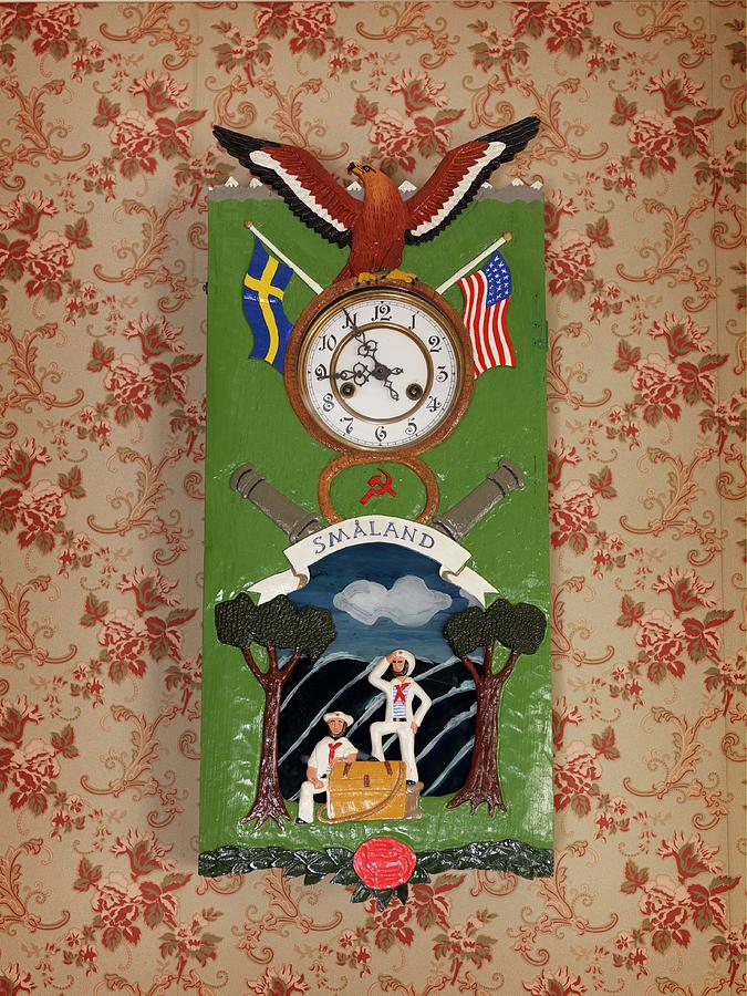 Clock With Flag And Eagle Motifs On Painted Metal Case Hung On Wall With Vintage-style Floral Wallpaper Photograph by Peter Carlsson