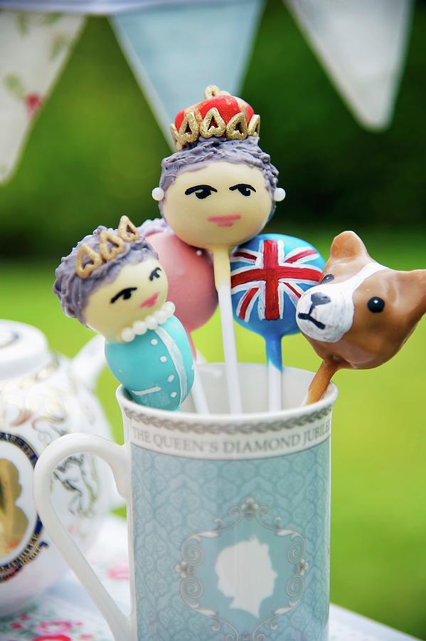 Close Up Of Funny Lollies Decorated As The Queen, A Union Jack And A Corgi In A British Tea Cup Photograph by Winfried Heinze