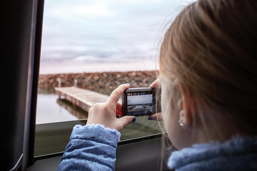 Girl Photograph - Close-up Of Girl Photographing Lake Through Window by Cavan Images