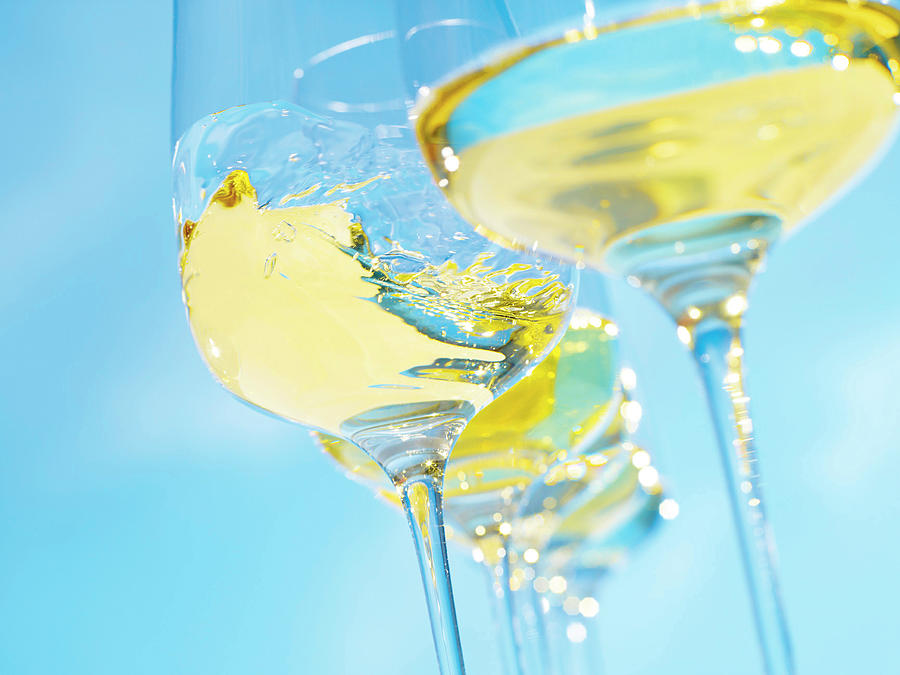 Close-up Of White Wine In Swung Glass On Blue Background Photograph by Jalag / Michael Holz