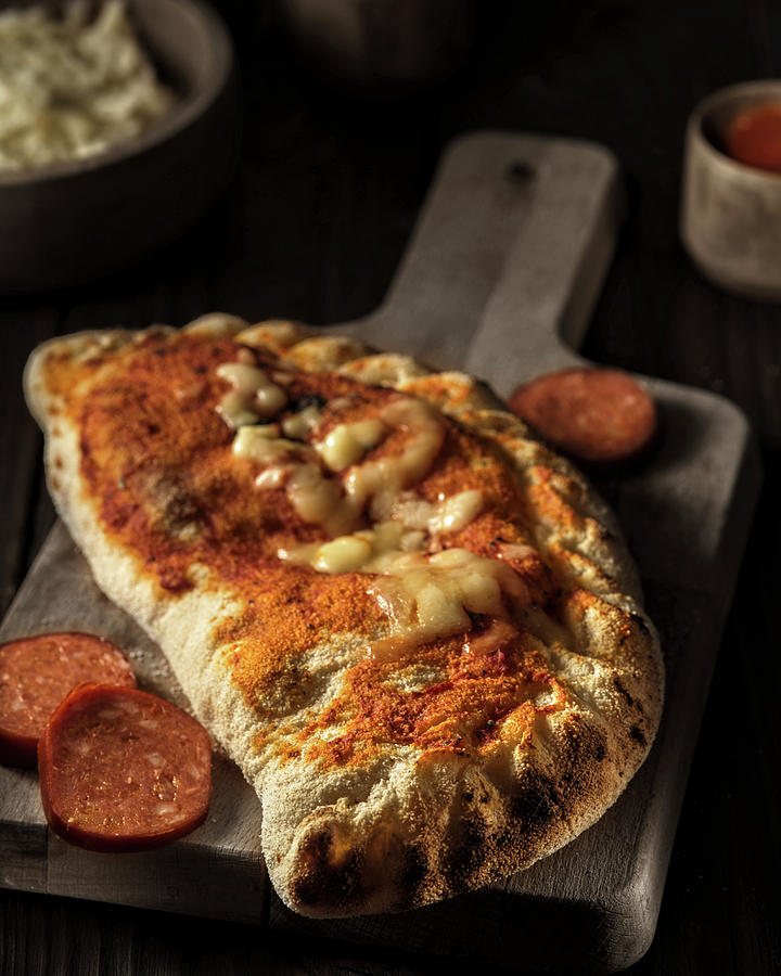 Closed Pizza calzone With Pepperoni Sausage Photograph by Reiand