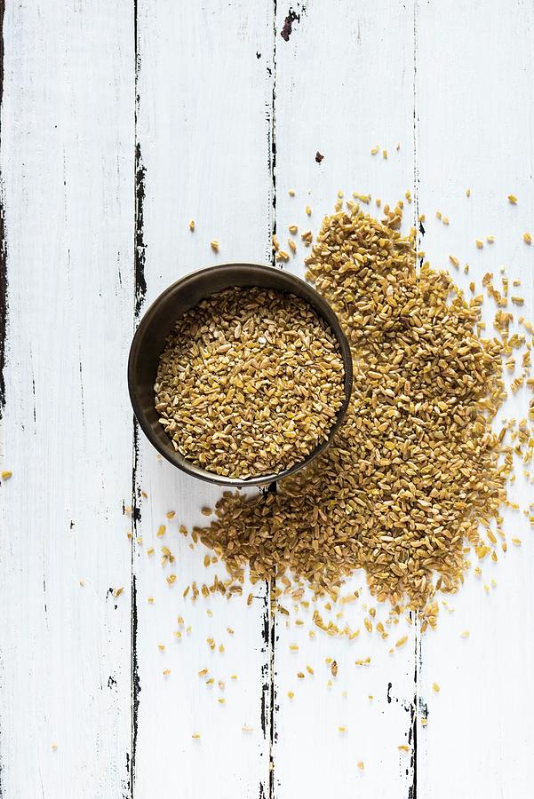 Coarsely Crushed Freekeh In A Bowl And On A Wooden Surface Photograph by Hein Van Tonder