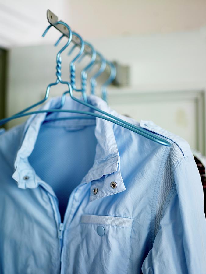 Coat Hangers With A Bright Blue Wind Breaker Hanging On A Rack Photograph by Per Magnus Persson